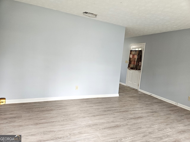 empty room featuring wood-type flooring and a textured ceiling