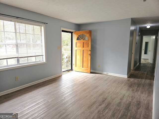 spare room featuring dark hardwood / wood-style flooring and a textured ceiling