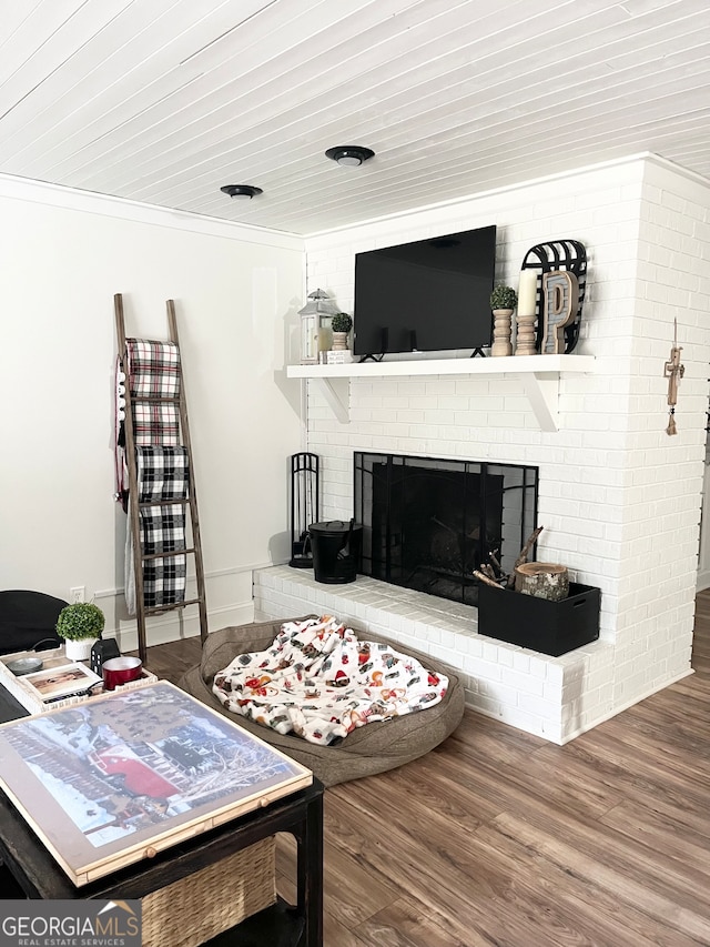 living room with wooden ceiling, hardwood / wood-style flooring, brick wall, a fireplace, and ornamental molding