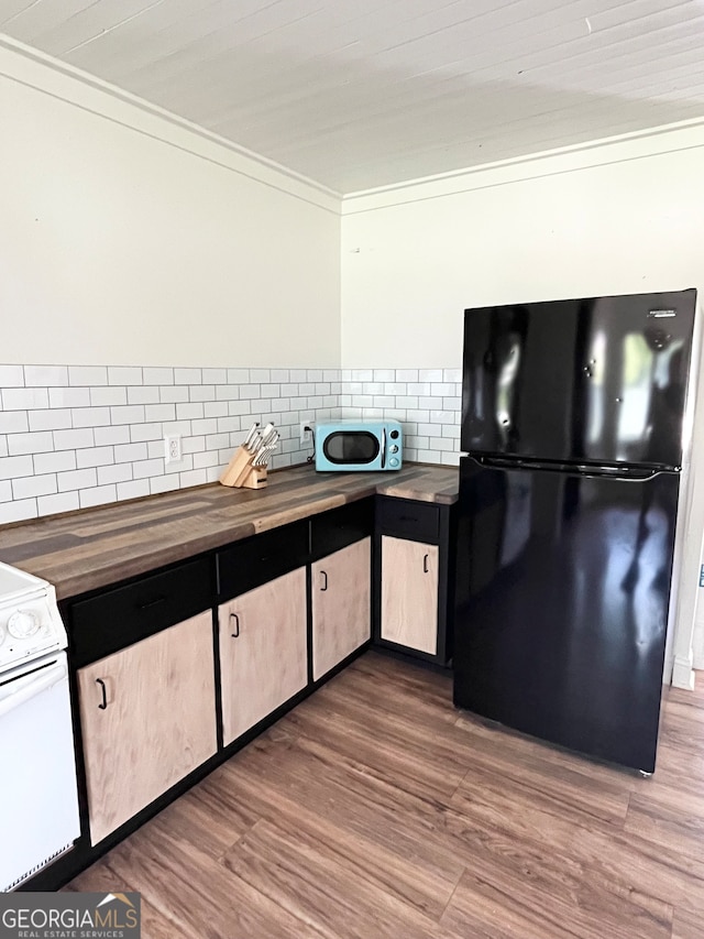 kitchen with white range, hardwood / wood-style flooring, black fridge, and wood counters