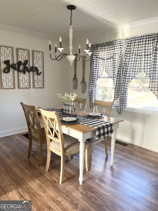 dining area with wood-type flooring, an inviting chandelier, and crown molding