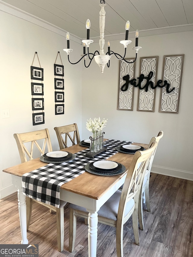 dining area with hardwood / wood-style floors, crown molding, and a notable chandelier