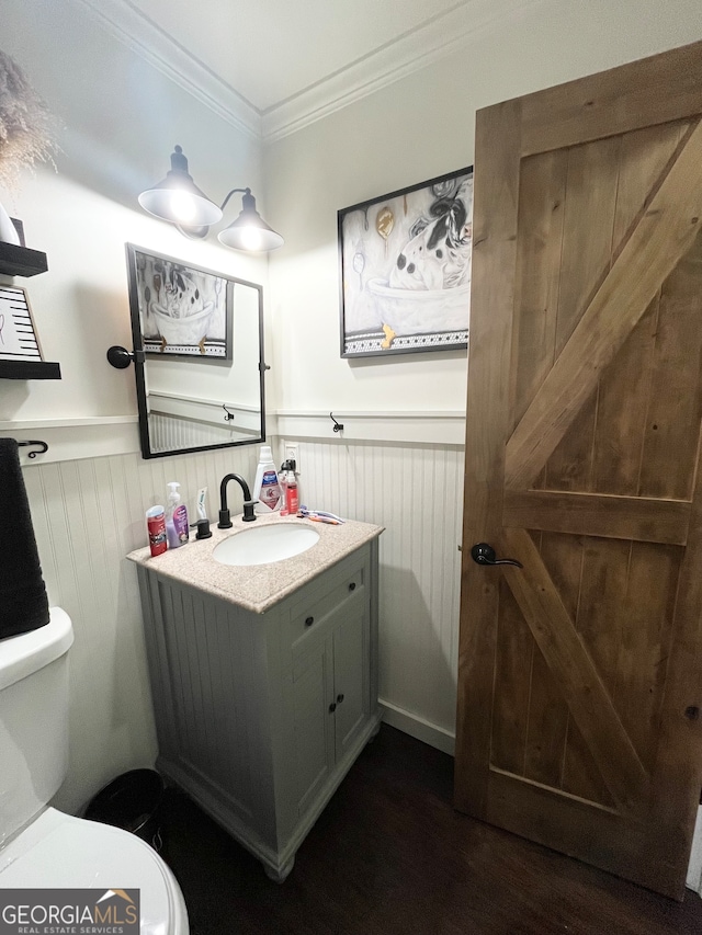 bathroom with crown molding, toilet, vanity, and wood-type flooring