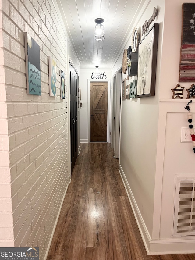 corridor featuring brick wall and hardwood / wood-style floors