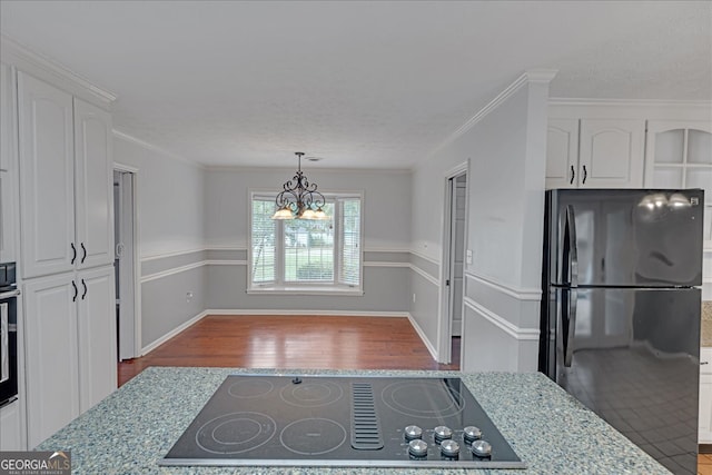 kitchen featuring a notable chandelier, black appliances, white cabinets, and hardwood / wood-style flooring