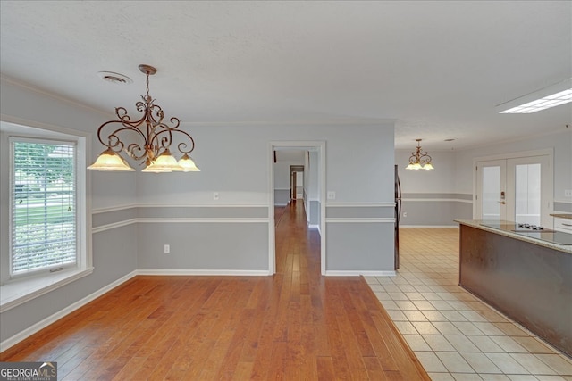 spare room with a chandelier, a healthy amount of sunlight, and light hardwood / wood-style floors