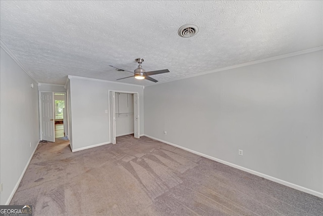 unfurnished bedroom featuring ceiling fan, a textured ceiling, ornamental molding, and carpet floors