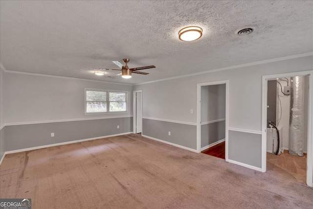 spare room featuring a textured ceiling, ornamental molding, ceiling fan, and carpet floors