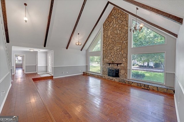 unfurnished living room featuring high vaulted ceiling, a fireplace, beamed ceiling, and a chandelier