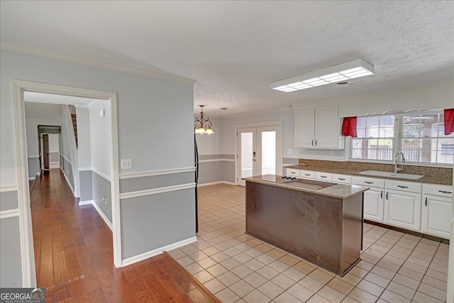 kitchen featuring light tile patterned floors, sink, a kitchen island, and white cabinetry