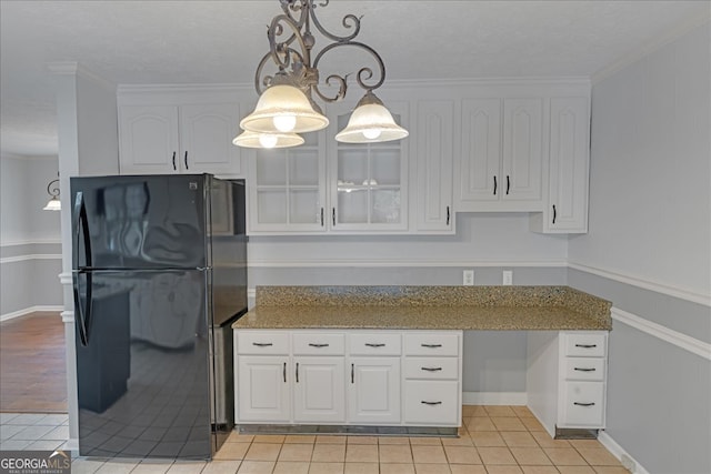 kitchen featuring white cabinets, crown molding, black refrigerator, and light tile patterned floors