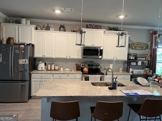 kitchen with stainless steel appliances, sink, a breakfast bar, and white cabinetry