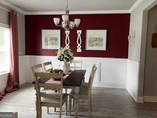 dining area with wood-type flooring, a chandelier, and ornamental molding