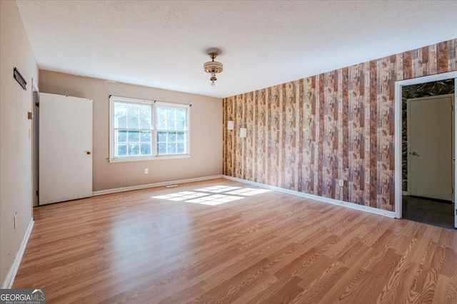 unfurnished room featuring a textured ceiling and light hardwood / wood-style flooring