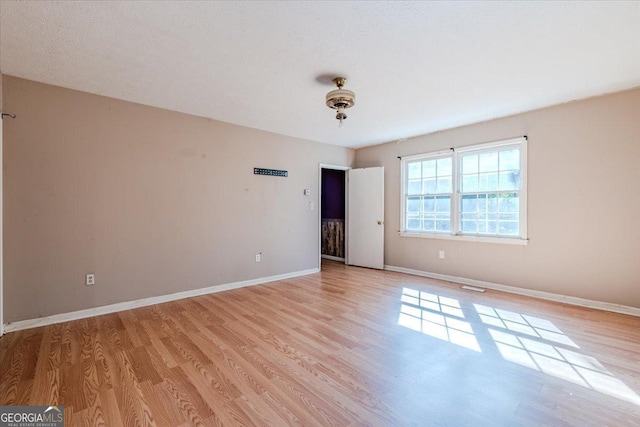 spare room featuring baseboards, visible vents, and light wood finished floors