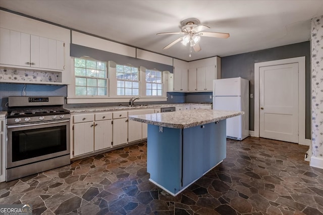 kitchen featuring ceiling fan, appliances with stainless steel finishes, white cabinetry, sink, and a center island