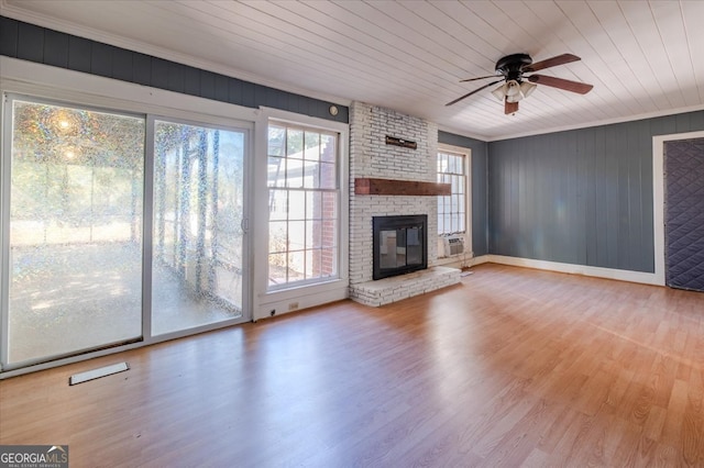 unfurnished living room with wood ceiling, crown molding, light wood-type flooring, a fireplace, and ceiling fan