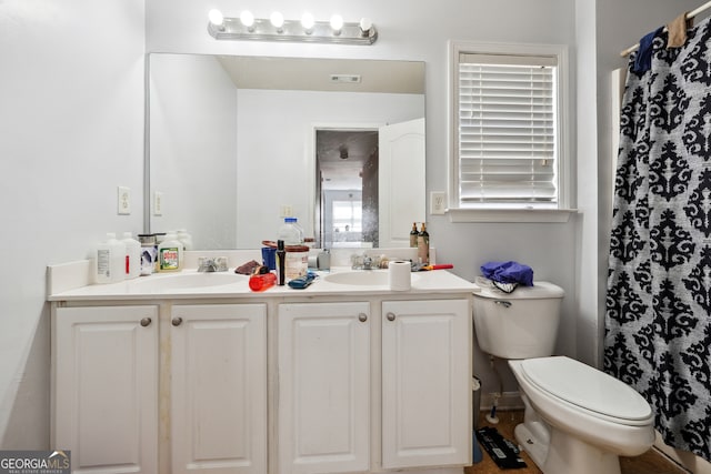 bathroom with toilet and dual vanity