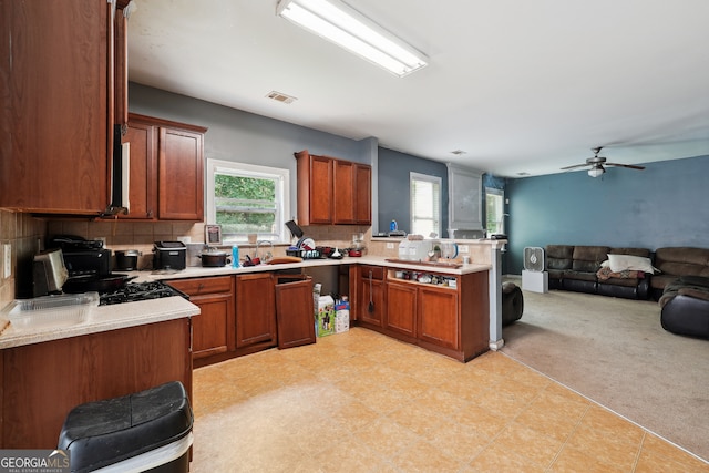 kitchen featuring ceiling fan, backsplash, light tile patterned floors, sink, and kitchen peninsula