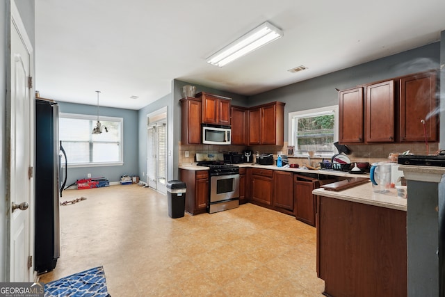 kitchen featuring backsplash, appliances with stainless steel finishes, sink, decorative light fixtures, and light tile patterned flooring