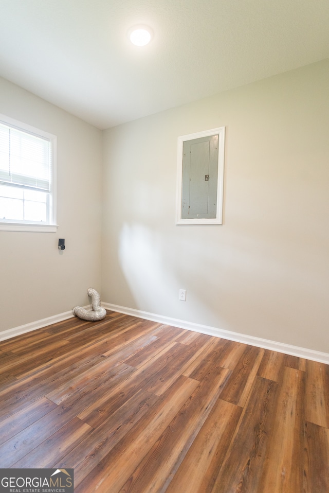 empty room with hardwood / wood-style floors and electric panel