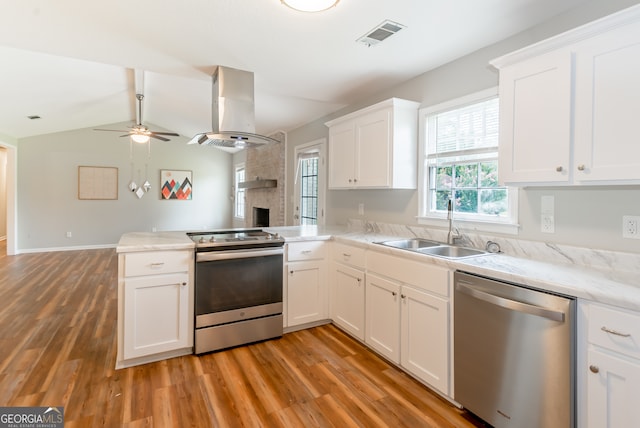 kitchen featuring light wood-type flooring, appliances with stainless steel finishes, island range hood, white cabinets, and kitchen peninsula