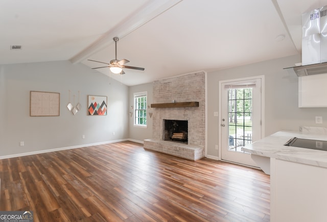 unfurnished living room with ceiling fan, vaulted ceiling with beams, hardwood / wood-style flooring, and a brick fireplace