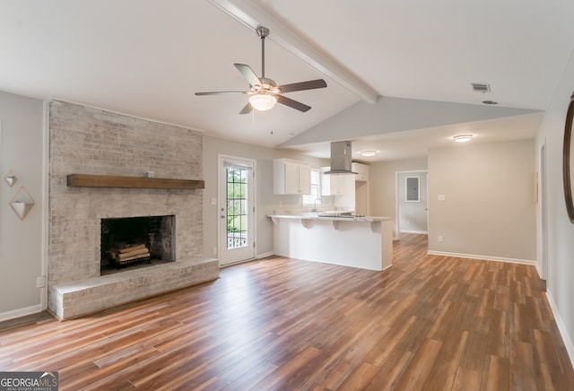 unfurnished living room featuring ceiling fan, a fireplace, lofted ceiling with beams, and wood-type flooring