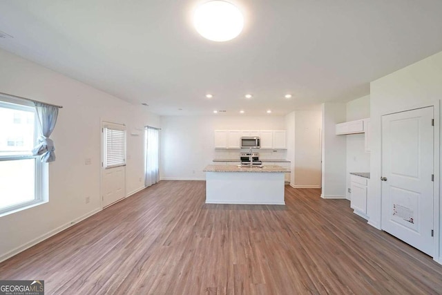 kitchen with stainless steel appliances, white cabinets, and wood finished floors