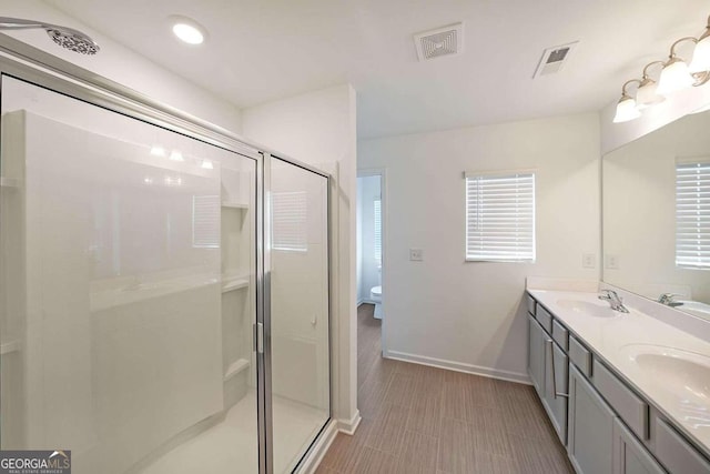 bathroom featuring double vanity, a shower stall, visible vents, and a sink