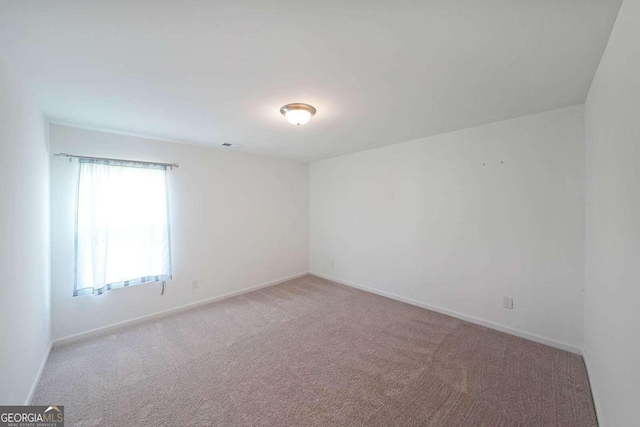 empty room featuring carpet flooring and baseboards