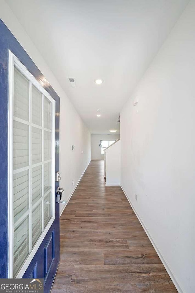 hallway with stairway, dark wood-style flooring, and visible vents