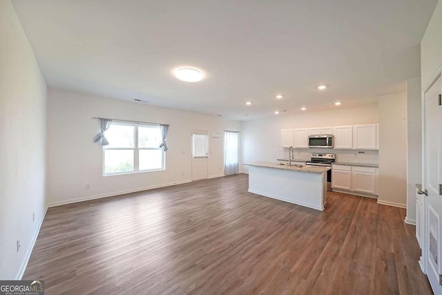 kitchen with appliances with stainless steel finishes, white cabinets, dark wood-style flooring, and open floor plan