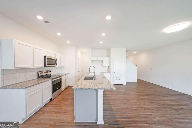 kitchen with stainless steel appliances, wood finished floors, a sink, white cabinetry, and decorative backsplash