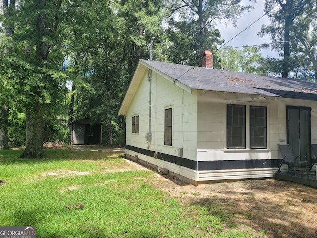 view of home's exterior with a lawn and a shed