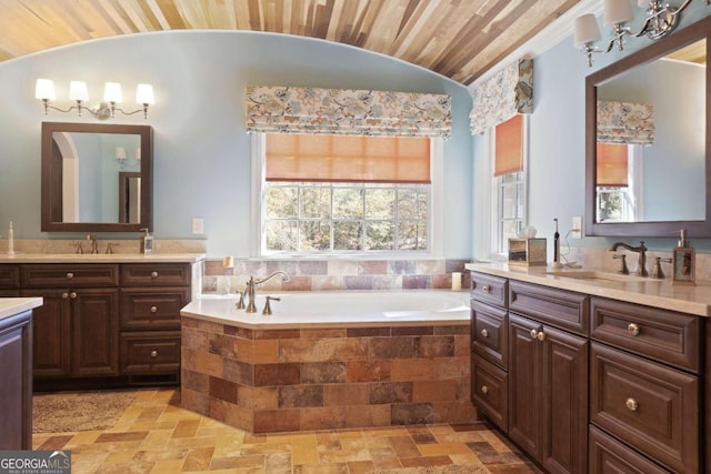 bathroom with tile patterned flooring, wood ceiling, a relaxing tiled tub, vaulted ceiling, and dual vanity