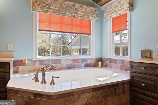 bathroom featuring tiled tub and vanity