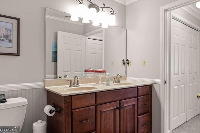 bathroom featuring ornamental molding, double vanity, and toilet