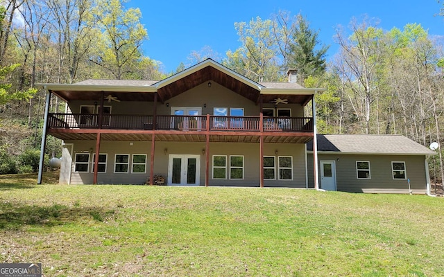 rear view of house featuring ceiling fan, french doors, and a lawn