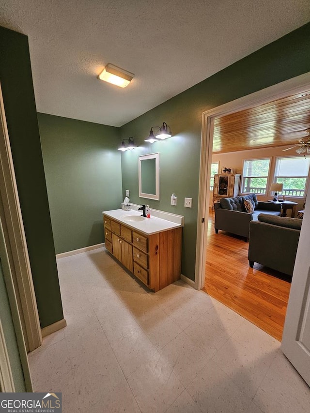 bathroom featuring ceiling fan, vanity, and a textured ceiling