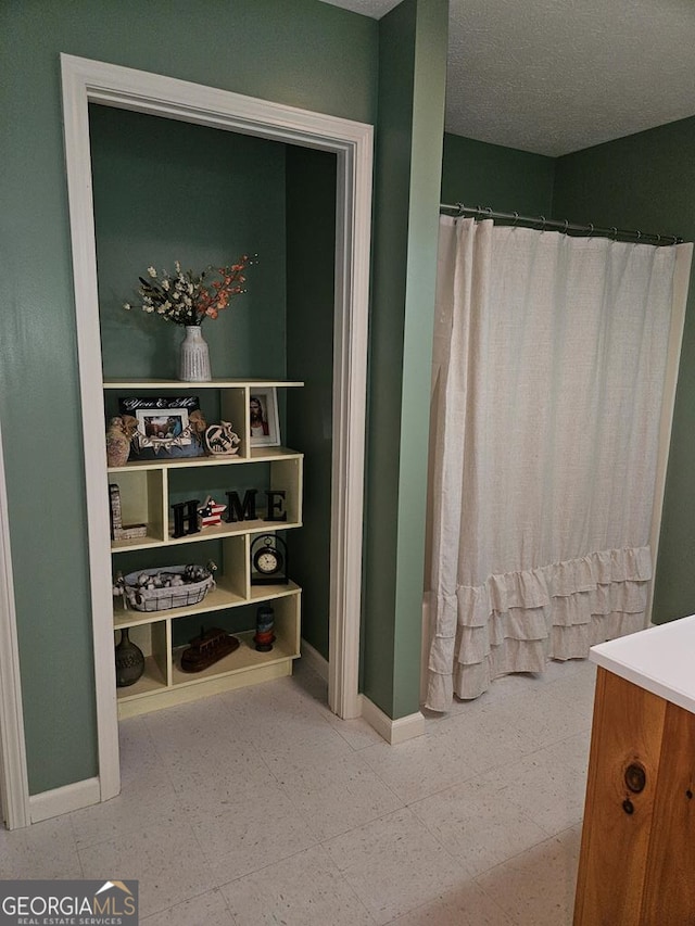 bathroom featuring a textured ceiling, walk in shower, and vanity