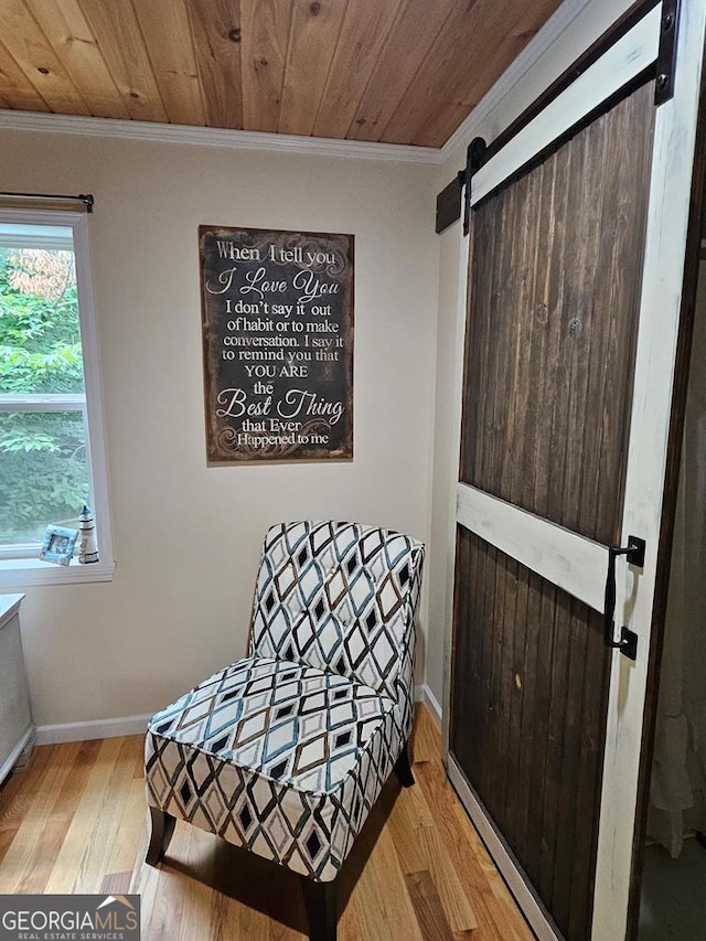 living area with a barn door, light wood-type flooring, crown molding, and wooden ceiling