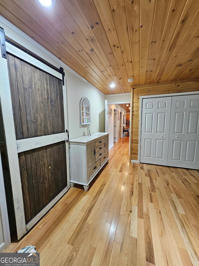 hall featuring a barn door, wood ceiling, and light hardwood / wood-style flooring