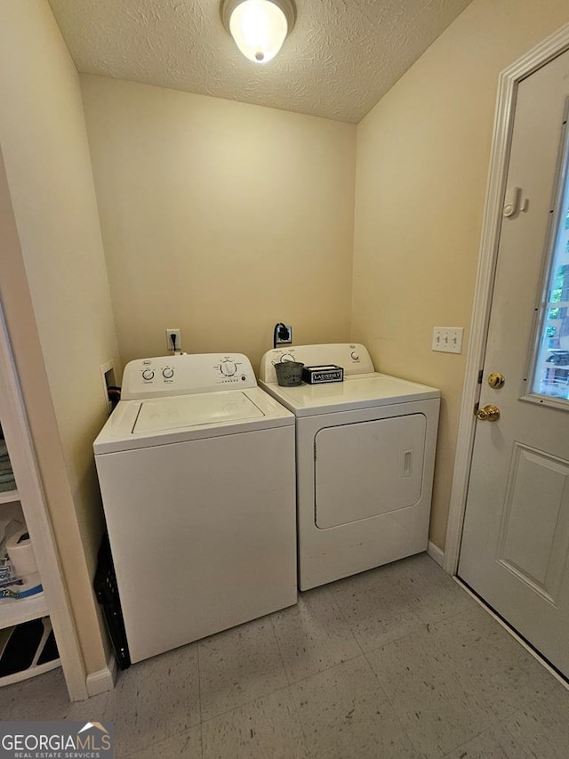 laundry room with a textured ceiling and washing machine and clothes dryer