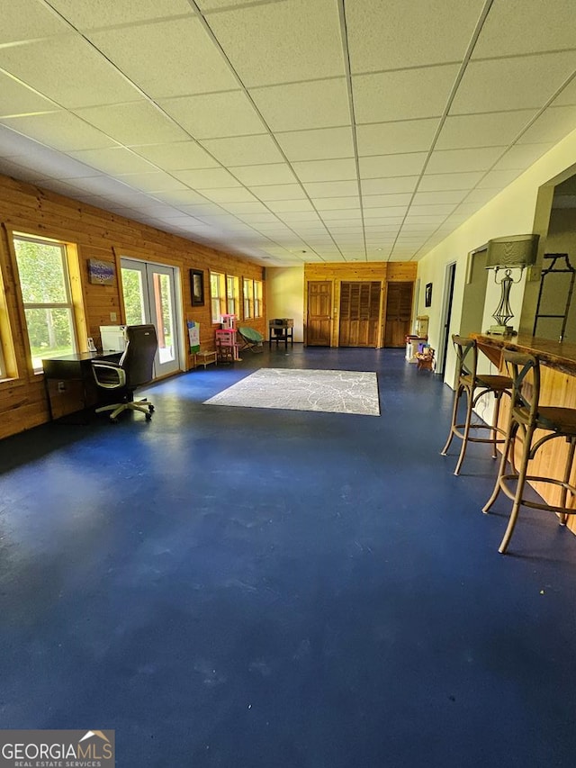 interior space featuring a drop ceiling and wooden walls