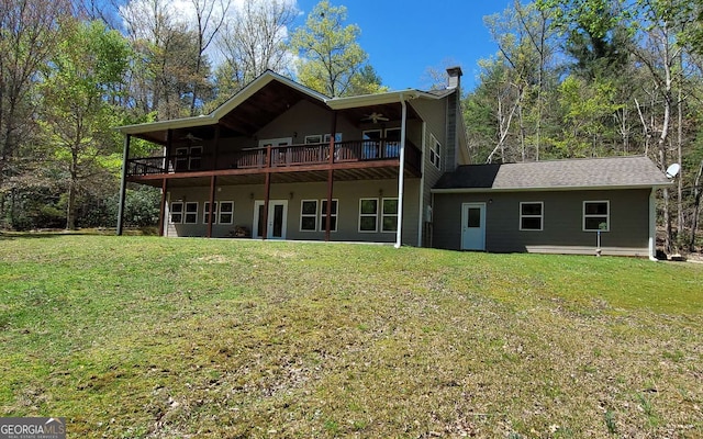 rear view of property with ceiling fan and a yard