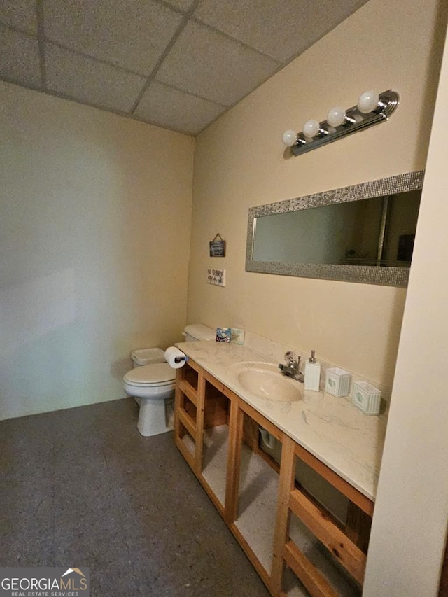 bathroom with toilet, vanity, and a paneled ceiling