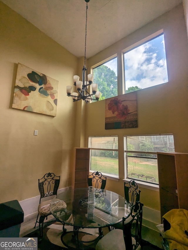 dining area featuring a towering ceiling and a notable chandelier