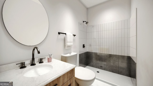 bathroom with a tile shower, vanity, and toilet