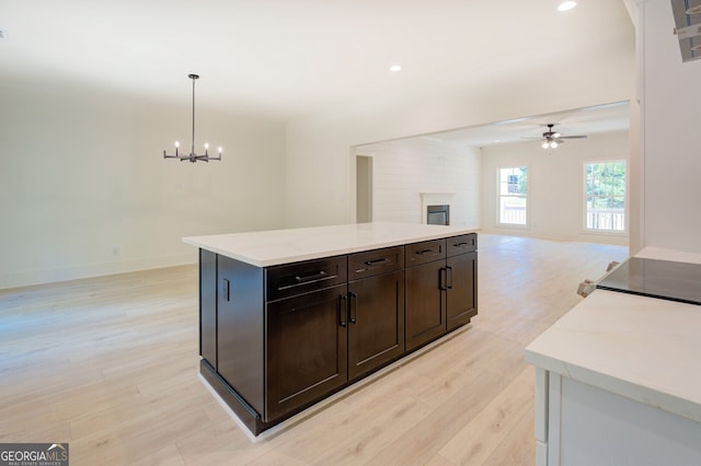 kitchen with ceiling fan with notable chandelier, decorative light fixtures, a kitchen island, and light hardwood / wood-style floors